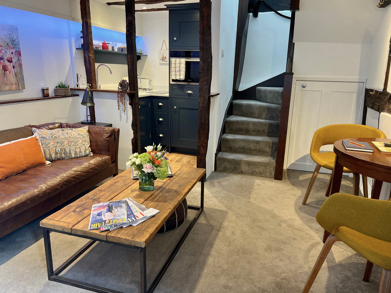 The lounge and dining area of Hideaway Cottage, with the staircase rising beside the kitchen