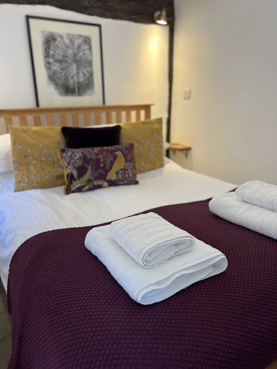 The double bedroom at Hideaway Cottage, made up with white linen under a beamed ceiling