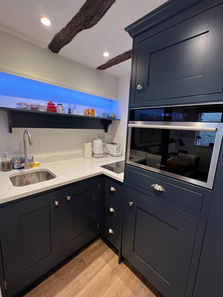 The navy shaker kitchen at Hideaway Cottage, with open shelving and a two-ring hob